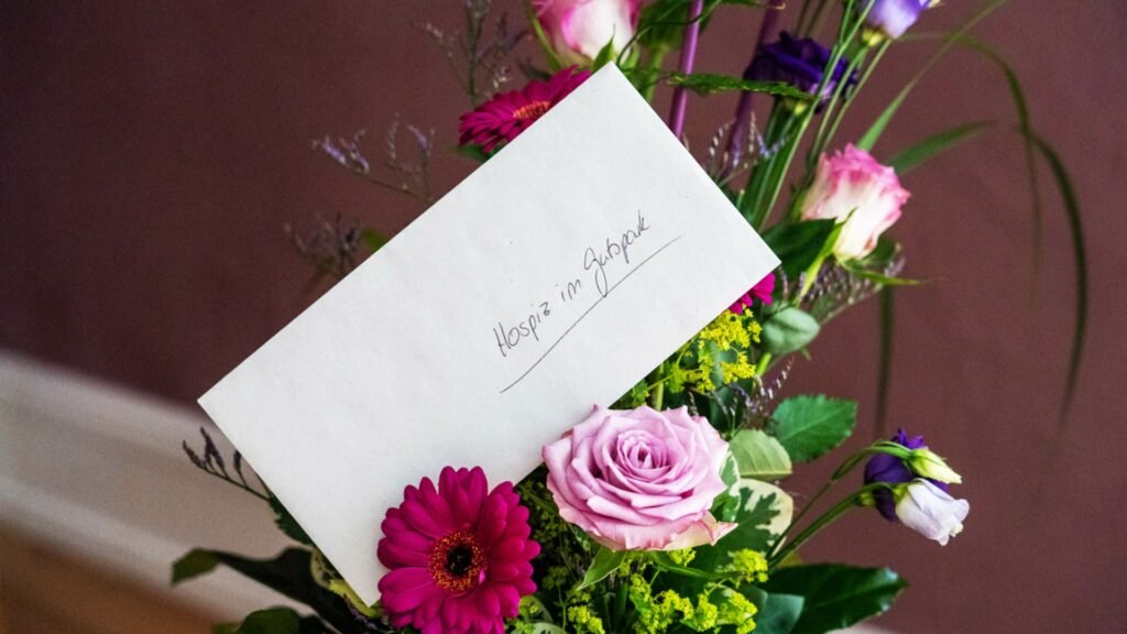 Ein Blumenstrauß mit einem Brief auf dem steht "Hospiz im Gutspark"